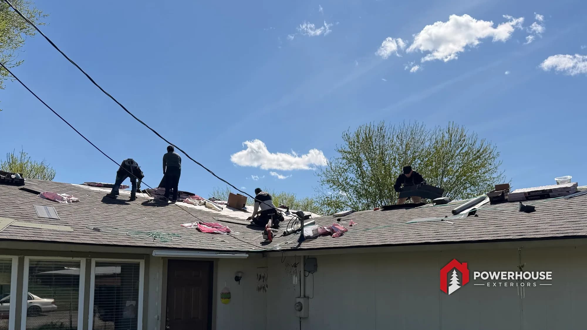 Roofing crew removing aging shingles from a Boise foothills home before replacement