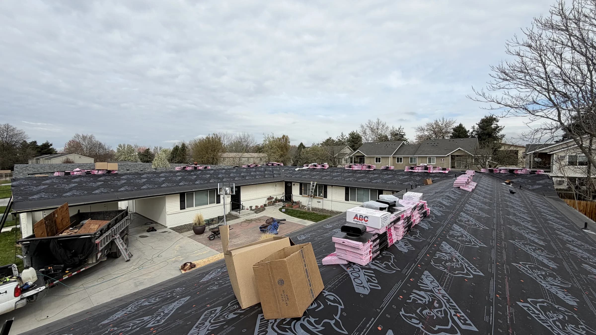 Synthetic underlayment and new shingles staged across a Boise multifamily roof