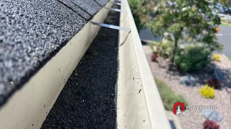 Shingle granules washed into a gutter, a sign of hail-worn roofing