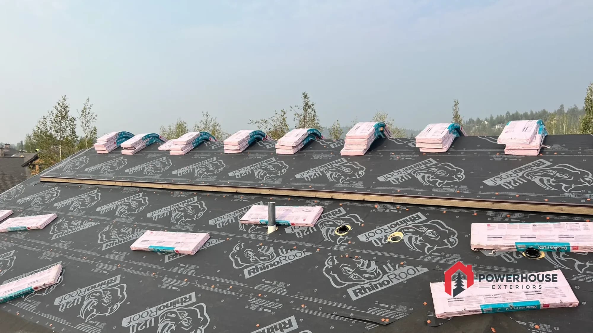 New impact-resistant shingles staged along a ridge over fresh underlayment