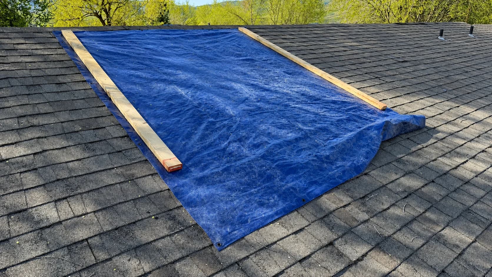 Treasure Valley Storm Damage Emergency Roof Tarp Emergency blue tarp secured over a damaged asphalt shingle roof in the Treasure Valley.